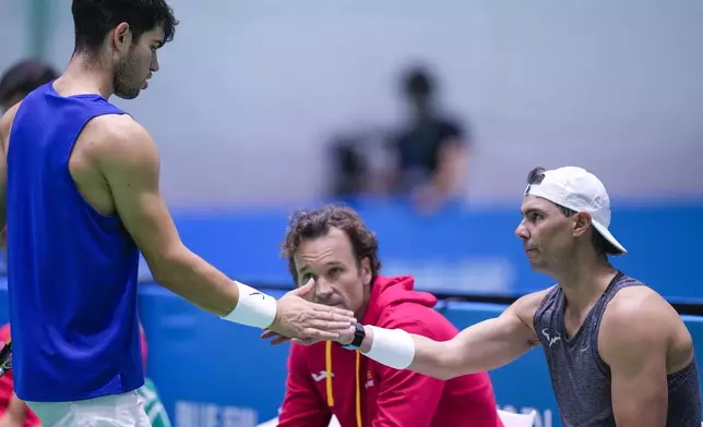 Spain's Carlos Alcaraz, left, shakes hands with Rafael Nadal during a training session at the Martin Carpena Sports Hall, in Malaga, southern Spain, on Sunday, Nov. 17, 2024. (AP Photo/Manu Fernandez)