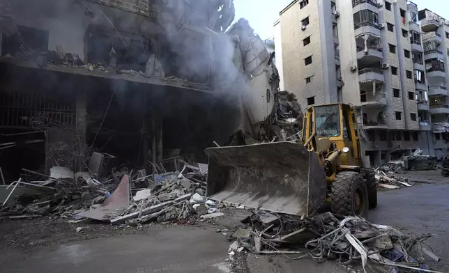 A bulldozer removes the rubble in front of a destroyed building that was hit Sunday night in an Israeli airstrike in Dahiyeh, in the southern suburb of Beirut, Lebanon, Monday, Nov. 25, 2024. (AP Photo/Hussein Malla)