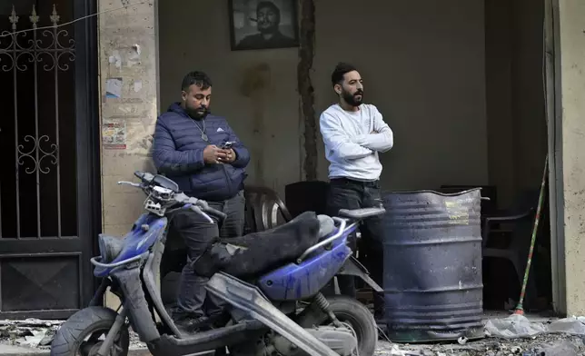 Lebanese men stand outside their damaged shop, as one of them looks at the destroyed building that was hit Sunday evening in an Israeli airstrike in Dahiyieh, in the southern suburb of Beirut, Lebanon, Monday, Nov. 25, 2024. (AP Photo/Hussein Malla)