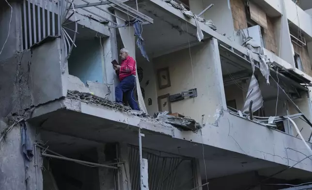 A man takes pictures by his mobile phone at his damaged apartment which was resulted from Sunday's Israeli airstrike in Dahiyeh, in the southern suburb of Beirut, Lebanon, Monday, Nov. 25, 2024. (AP Photo/Hussein Malla)