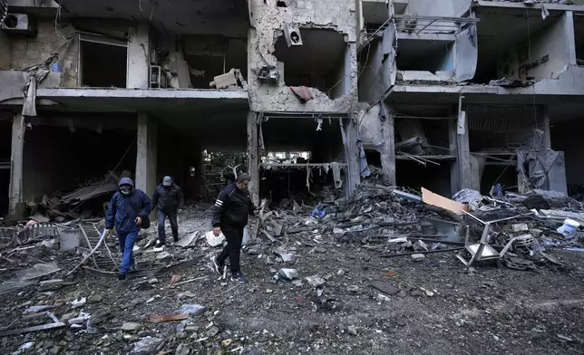 Residents pass in front of destroyed building which was resulted from Sunday's Israeli airstrike in Dahiyeh, in the southern suburb of Beirut, Lebanon, Monday, Nov. 25, 2024. (AP Photo/Hussein Malla)