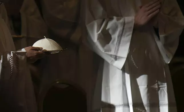 A priest carries Pope Francis skull-cap as he presides over a mass on the occasion of the World Day of the Poor in St. Peter's Basilica, at the Vatican, Sunday, Nov. 17, 2024. (AP Photo/Alessandra Tarantino)