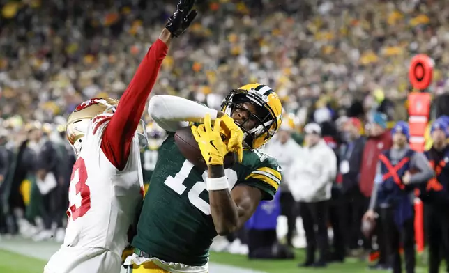 Green Bay Packers wide receiver Malik Heath (18) catches a touchdown pass against San Francisco 49ers cornerback Rock Ya-Sin (33) during the second half of an NFL football game on Sunday, Nov. 24, 2024 in Green Bay, Wis. (AP Photo/Mike Roemer)