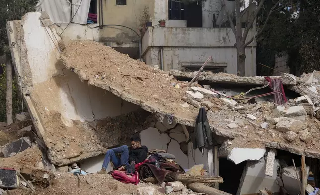 A man sits on the rubble of a destroyed house in Baalbek, eastern Lebanon, Thursday, Nov. 28, 2024. (AP Photo/Hassan Ammar)