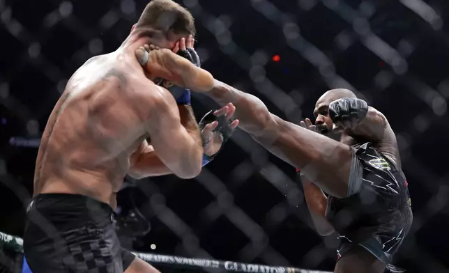 Jon Jones, right, kicks Stipe Miocic in a UFC 309 mixed martial arts heavyweight title bout, early on Sunday, Nov. 17, 2024, in New York. (AP Photo/Adam Hunger)