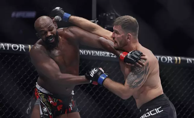 Stipe Miocic, right, punches Jon Jones in a UFC 309 mixed martial arts heavyweight title bout, early on Sunday, Nov. 17, 2024, in New York. (AP Photo/Adam Hunger)