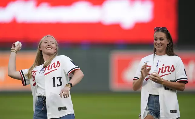 FILE - Minnesota Frost's Grace Zumwinkle, left, throws out a ceremonial first pitch as teammate Taylor Heise, right, watches before a baseball game between the Los Angeles Angels and the Minnesota Twins, Sept. 9, 2024, in Minneapolis. (AP Photo/Abbie Parr, File)