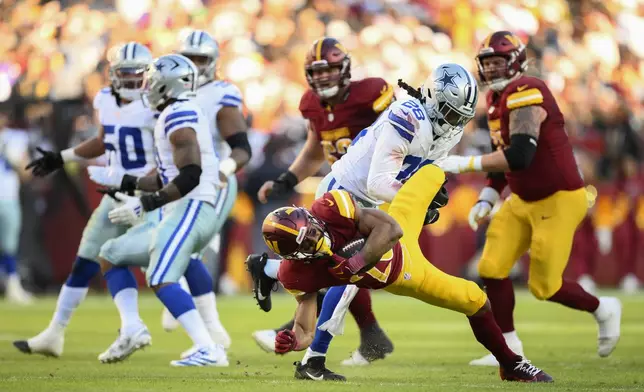 Washington Commanders running back Jeremy McNichols (26) is tackled by Dallas Cowboys safety Malik Hooker (28) during the second half of an NFL football game, Sunday, Nov. 24, 2024, in Landover, Md. (AP Photo/Nick Wass)