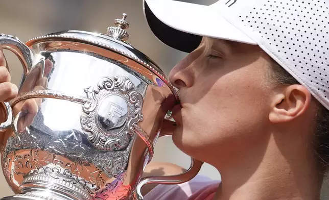 FILE - Poland's Iga Swiatek kisses the trophy after winning the women's final of the French Open tennis tournament against Italy's Jasmine Paolini at the Roland Garros stadium in Paris, France, Saturday, June 8, 2024. (AP Photo/Thibault Camus, File)