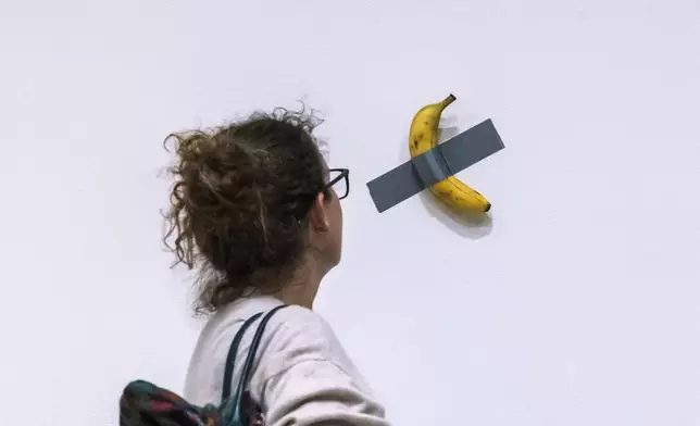 File - A woman looks at artist Maurizio Cattelan's piece of art "Comedian" during an auction preview at Sotheby's in New York, Monday, Nov. 11, 2024. (AP Photo/Eduardo Munoz Alvarez, File)