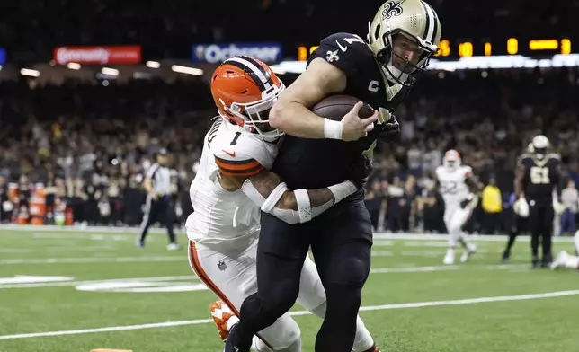 New Orleans Saints tight end Taysom Hill (7) scores as Cleveland Browns safety Juan Thornhill (1) defends in the first half of an NFL football game in New Orleans, Sunday, Nov. 17, 2024. (AP Photo/Butch Dill)