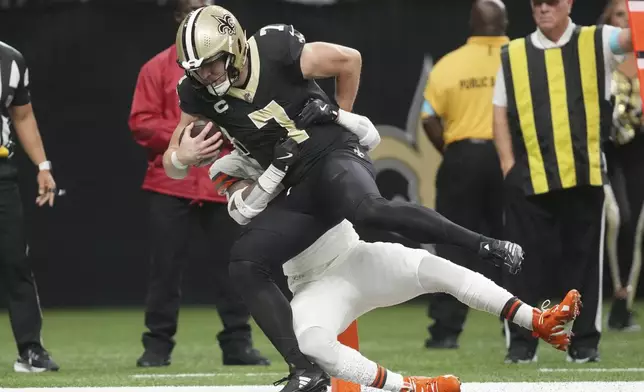 New Orleans Saints tight end Taysom Hill (7) is brought down by Cleveland Browns safety Juan Thornhill, rear, as he scores in the first half of an NFL football game in New Orleans, Sunday, Nov. 17, 2024. (AP Photo/Gerald Herbert)