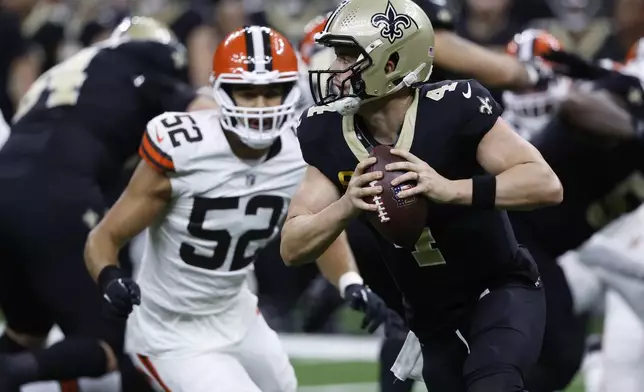 New Orleans Saints quarterback Derek Carr (4) rolls out in front of Cleveland Browns linebacker Elerson G. Smith (52) to pass to wide receiver Marquez Valdes-Scantling for a touchdown in the first half of an NFL football game in New Orleans, Sunday, Nov. 17, 2024. (AP Photo/Butch Dill)