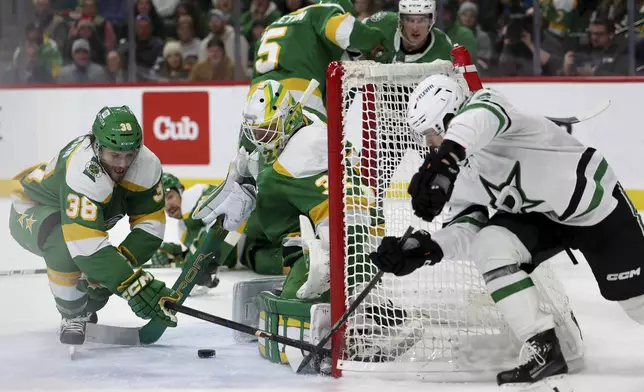 Dallas Stars center Mavrik Bourque, right, attempts to score while Minnesota Wild right wing Ryan Hartman (38) and Wild goaltender Filip Gustavsson (32) keep the puck out of the net during the second period of an NHL hockey game, Saturday, Nov. 16, 2024, in St. Paul, Minn. (AP Photo/Ellen Schmidt)