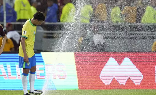 Brazil's Marquinhos attempts to stop the sprinklers that were turned on during a FIFA World Cup 2026 qualifying soccer match against Venezuela at Monumental stadium in Maturin, Venezuela, Thursday, Nov. 14, 2024. (AP Photo/Ariana Cubillos)