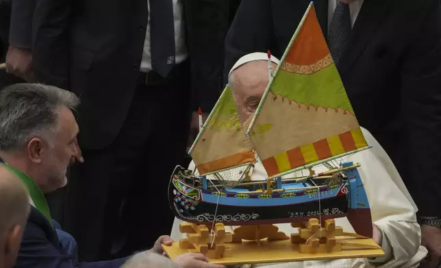 Pope Francis is presented with a model of a fishing boat during an audience with fishermen and members of the CEI, Italians Bishops Conference, in the Pope Paul VI hall at the Vatican, Saturday, Nov. 23, 2024. (AP Photo/Andrew Medichini)