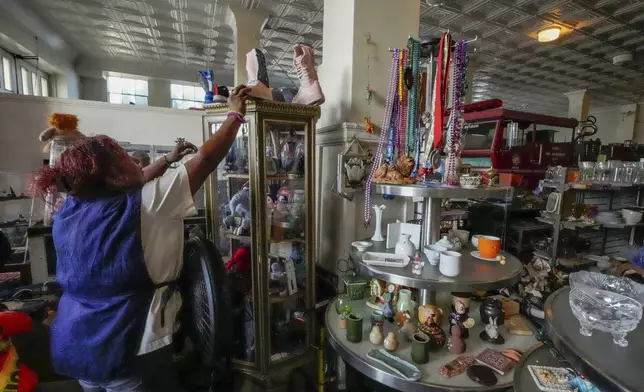 Employee Marylin Moreno, originally from El Salvador, a minimum wage earner, grabs a pair of booths for a client at community thrift store in Los Angeles on Oct. 11, 2024. (AP Photo/Damian Dovarganes)