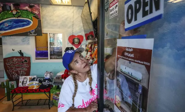 Business owner Silvia Navarro, who recently opened a dog and cat food supply store, adjusts a sign at her store in Los Angeles on Oct. 11, 2024. (AP Photo/Damian Dovarganes)