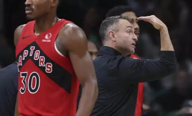 Toronto Raptors head coach Darko Rajakovic calls signals as Toronto Raptors guard Ochai Agbaji (30) walks off the court during the first half of an NBA basketball game, Saturday, Nov. 16, 2024, in Boston. (AP Photo/Mark Stockwell)