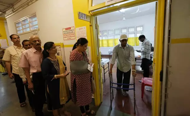 People wait in a queue to cast their votes during Maharashtra state assembly elections in Mumbai, India, Wednesday, Nov 20, 2024. (AP Photo/Rajanish Kakade)