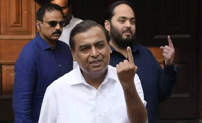 Chairman and managing director of Reliance Industries Mukesh Ambani and his son Anant Ambani show index finger after casting her votes during Maharashtra state assembly elections in Mumbai, India, Wednesday, Nov. 20, 2024.(AP Photo/Rajanish Kakade)