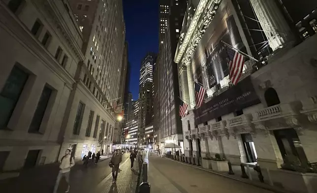 People pass the New York Stock Exchange, right, on Wednesday, Nov. 13, 2024, in New York. (AP Photo/Peter Morgan)