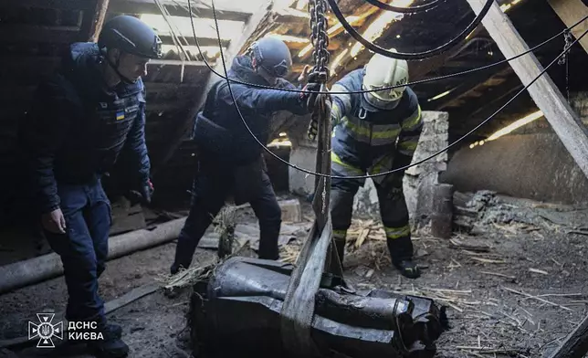 In this photo provided by the Ukrainian Emergency Service, emergency services personnel remove part of a Russian missile that hit an apartment house during massive missile attack in Kyiv, Ukraine, Sunday, Nov. 17, 2024. (Ukrainian Emergency Service via AP)