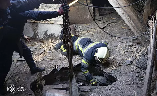 In this photo provided by the Ukrainian Emergency Service, emergency services personnel remove part of a Russian missile that hit an apartment house during massive missile attack in Kyiv, Ukraine, Sunday, Nov. 17, 2024. (Ukrainian Emergency Service via AP)