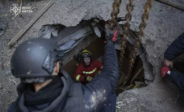 In this photo provided by the Ukrainian Emergency Service, emergency services personnel remove part of a Russian missile that hit an apartment house during massive missile attack in Kyiv, Ukraine, Sunday, Nov. 17, 2024. (Ukrainian Emergency Service via AP)