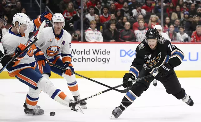 Washington Capitals defenseman John Carlson (74) shoots the puck against New York Islanders defenseman Scott Mayfield, left, during the first period of an NHL hockey game, Friday, Nov. 29, 2024, in Washington. (AP Photo/Nick Wass)