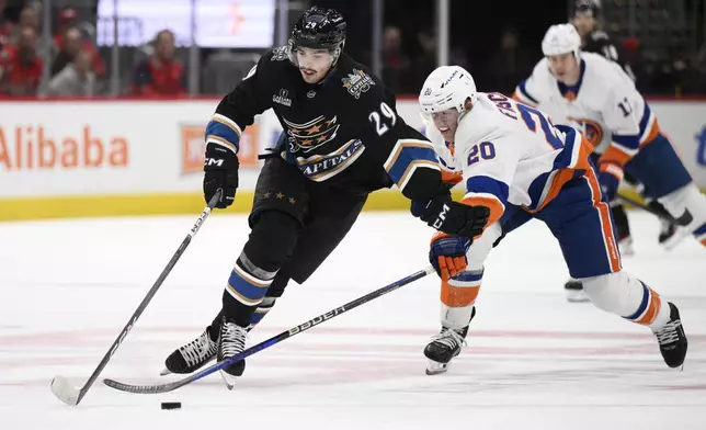 Washington Capitals center Hendrix Lapierre (29) skates with the puck past New York Islanders right wing Hudson Fasching (20) during the first period of an NHL hockey game, Friday, Nov. 29, 2024, in Washington. (AP Photo/Nick Wass)