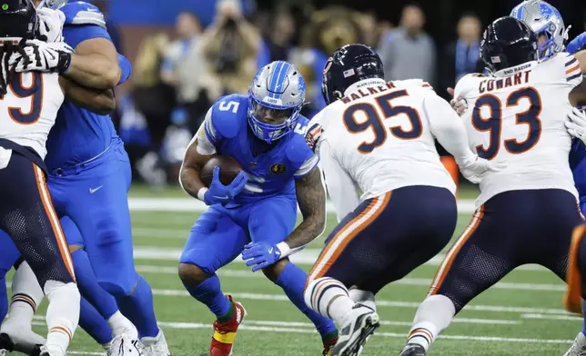 Detroit Lions running back David Montgomery (5) looks for running room as Chicago Bears defensive end DeMarcus Walker (95) defends during the first half of an NFL football game, Sunday, Nov. 17, 2024, in Detroit. (AP Photo/Carlos Osorio)