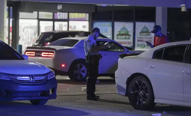 A New Orleans police officer takes a report at the scene in the Save O Lot parking lot where several people were shot and killed in New Orleans Sunday Nov. 17, 2024. (David Grunfeld/The Times-Picayune/The New Orleans Advocate via AP)