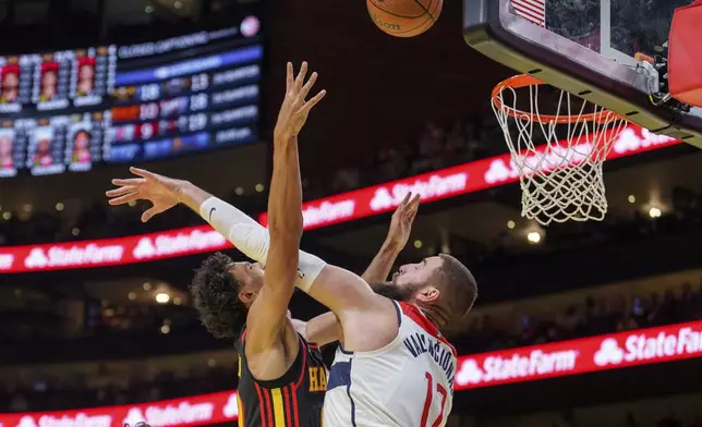 Atlanta Hawks forward Zaccharie Risacher, left, attempts a layup over Washington Wizards center Jonas Valanciunas, right, during the first half of an Emirates NBA Cup basketball game, Friday, Nov. 15, 2024, in Atlanta. (AP Photo/Jason Allen)