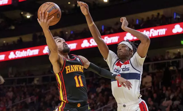 Atlanta Hawks guard Trae Young (11) goes up for a layup while guarded by Washington Wizards guard Bilal Coulibaly, right, during the first half of an Emirates NBA Cup basketball game, Friday, Nov. 15, 2024, in Atlanta. (AP Photo/Jason Allen)