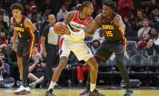 Atlanta Hawks center Clint Capela (15) plays defense on Washington Wizards forward Alexandre Sarr, center, during the first half of an Emirates NBA Cup basketball game, Friday, Nov. 15, 2024, in Atlanta. (AP Photo/Jason Allen)