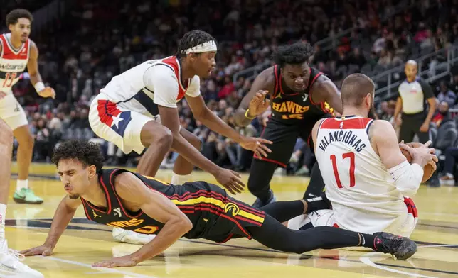 Atlanta Hawks forward Zaccharie Risacher, left, falls while trying to get a rebound against Washington Wizards center Jonas Valanciunas (17) during the first half of an Emirates NBA Cup basketball game, Friday, Nov. 15, 2024, in Atlanta. (AP Photo/Jason Allen)