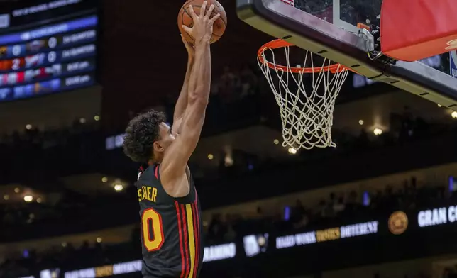 Atlanta Hawks forward Zaccharie Risacher (10) slam dunks the ball during the first half of an Emirates NBA Cup basketball game against the Washington Wizards, Friday, Nov. 15, 2024, in Atlanta. (AP Photo/Jason Allen)