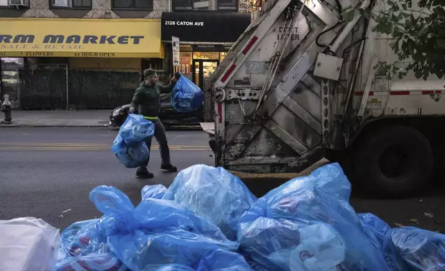 A sanitation worker collects trash, Saturday, Nov. 16, 2024, in the Brooklyn borough of New York. (AP Photo/Yuki Iwamura)