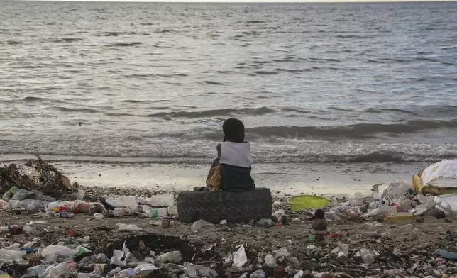 FILE- A boy sits on a tire among garbage during sunset at a beach in Saint-Marc, Haiti, Thursday, Oct. 10, 2024. (AP Photo/Odelyn Joseph, File)