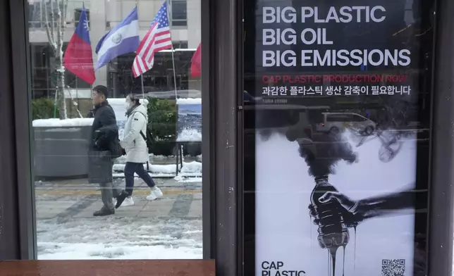 People pass by a poster calling for a reduction in plastic production while the fifth session of the Intergovernmental Negotiating Committee on Plastic Pollution is being held in Busan, at a bus station in Seoul, South Korea, Thursday, Nov. 28, 2024. (AP Photo/Ahn Young-joon)