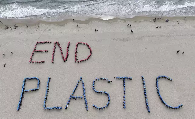 Environment activists perform a human sign calling for a strong global plastics treaty ahead of the fifth session of the Intergovernmental Negotiating Committee on Plastic Pollution which sets to be held from Nov. 25 to Dec. 1 on the beach in Busan, South Korea, Sunday, Nov. 24, 2024. (Son Hyung-joo/Yonhap via AP)