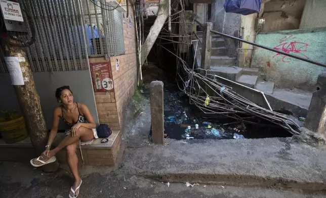 Carla do Nascimento Gomes sits in an alley where sewage water passes through the Rocinha favela in Rio de Janeiro, Wednesday, Nov. 6, 2024. (AP Photo/Bruna Prado)