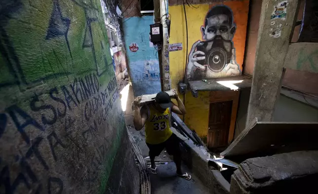 A local carries building materials up an alley in the Rocinha favela of Rio de Janeiro, Wednesday, Nov. 6, 2024. (AP Photo/Bruna Prado)