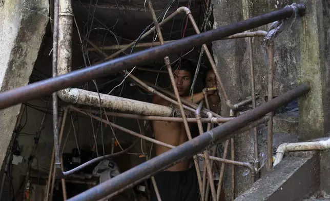 Residents repair a water line to their home amid a labyrinth of pipes in the Rocinha favela of Rio de Janeiro, Wednesday, Nov. 6, 2024. (AP Photo/Bruna Prado)