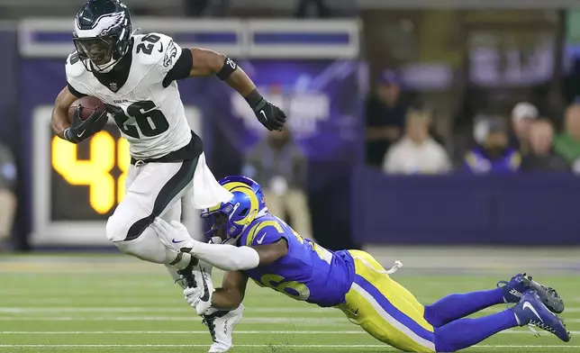 Philadelphia Eagles running back Saquon Barkley, left, runs against Los Angeles Rams safety Kamren Kinchens during the first half of an NFL football game in Inglewood, Calif., Sunday, Nov. 24, 2024. (AP Photo/Ryan Sun)