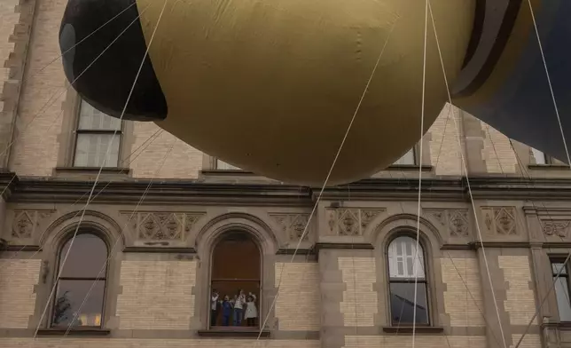 Spectators watch from a window as the balloon floats by along Central Park West during the Macy's Thanksgiving Day Parade, Thursday, Nov. 28, 2024, in New York. (AP Photo/Yuki Iwamura)