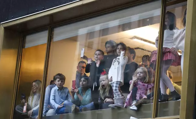 People watch from a window inside as the Macy's Thanksgiving Day Parade goes by Thursday, Nov. 28, 2024, in New York. (AP Photo/Heather Khalifa)