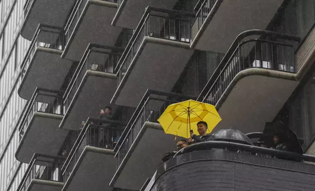 People watch from their balconies above during the Macy's Thanksgiving Day Parade, Thursday, Nov. 28, 2024, in New York. (AP Photo/Heather Khalifa)