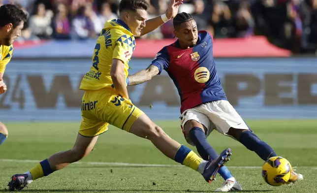 Barcelona's Raphinha, right, and Las Palmas' Mika Marmol fight for the ball during a Spanish La Liga soccer match at the Lluis Companys Olympic Stadium in Barcelona, Spain, Saturday Nov. 30, 2024. (AP Photo/Joan Monfort)